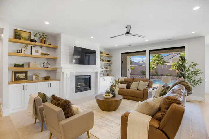 Built-in cabinetry with wood shelving, a fireplace with a shiplap surround, recessed lighting, wood-finish flooring, and sliding glass doors opening to the backyard with a pool