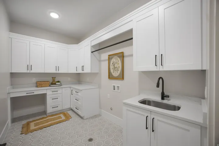 Built-in white cabinetry, light-toned hexagon tile flooring, stainless steel sink with a matte black faucet, and ample countertop space