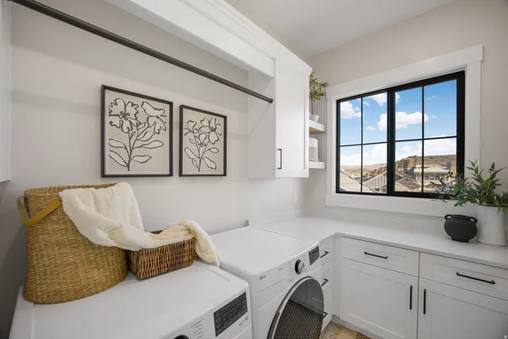 White shaker cabinetry with matte black hardware, solid surface countertops, a built-in hanging rod, and natural light from a multi-pane window