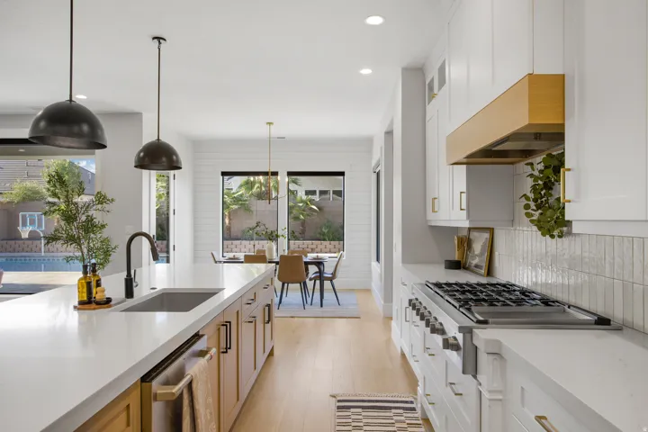 Gourmet kitchen with an expansive island, stainless steel appliances, wood-finish flooring, a contemporary range hood, and ample cabinetry