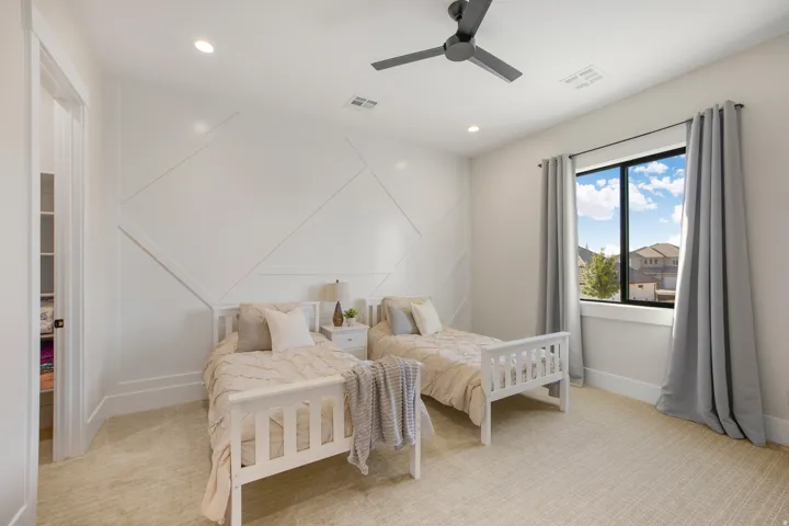 Textured accent wall, recessed lighting, ceiling fan, large window, and light-toned carpet flooring