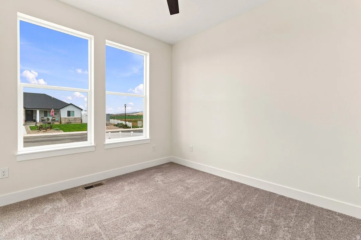 Dual pane windows, neutral wall tones, textured carpeting, and a ceiling fan