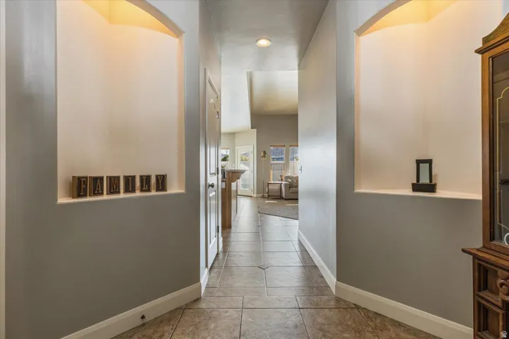Hallway featuring tile flooring, recessed ceiling lighting, and two arched wall niches with integrated lighting