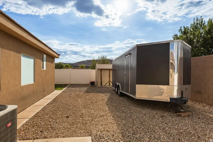 Gravel side yard with a white vinyl fence and stucco exterior