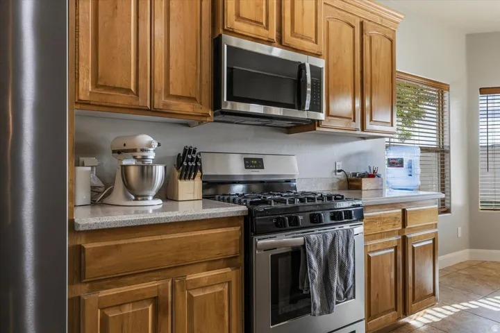 Kitchen featuring wood cabinetry, stainless steel microwave, gas range with oven, and light-toned countertops