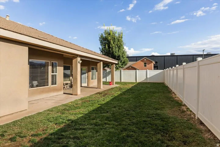 Expansive backyard featuring a covered patio, stucco exterior, and a privacy fence