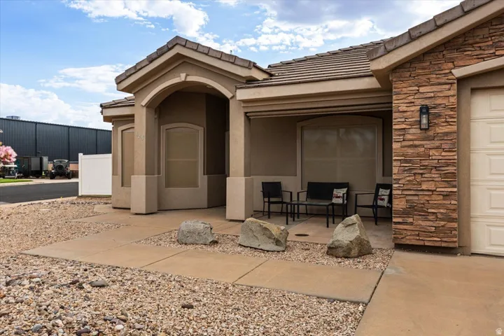 Exterior features stucco siding, stacked stone accents, a tile roof, and a covered patio area