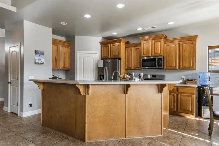 Kitchen featuring wood cabinetry, a center island with countertop seating, stainless steel appliances, recessed lighting, and tile flooring