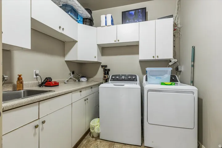 Washer and dryer units, white cabinetry, integrated sink, and light-toned countertops