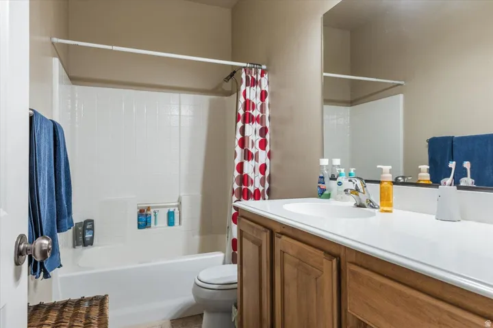 Vanity with wood-finish cabinetry, integrated sink, and expansive mirror