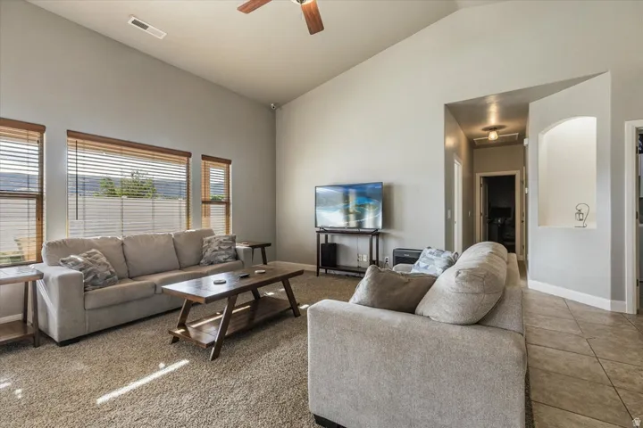 Vaulted ceilings, multiple windows with natural wood blinds, overhead ceiling fan, and an arched wall niche