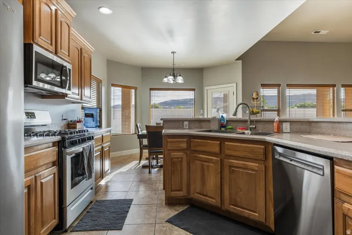 Kitchen featuring wood cabinetry, stainless steel appliances, a double basin sink, and tile flooring