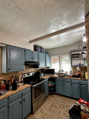 Kitchen featuring blue cabinetry, a stainless steel range