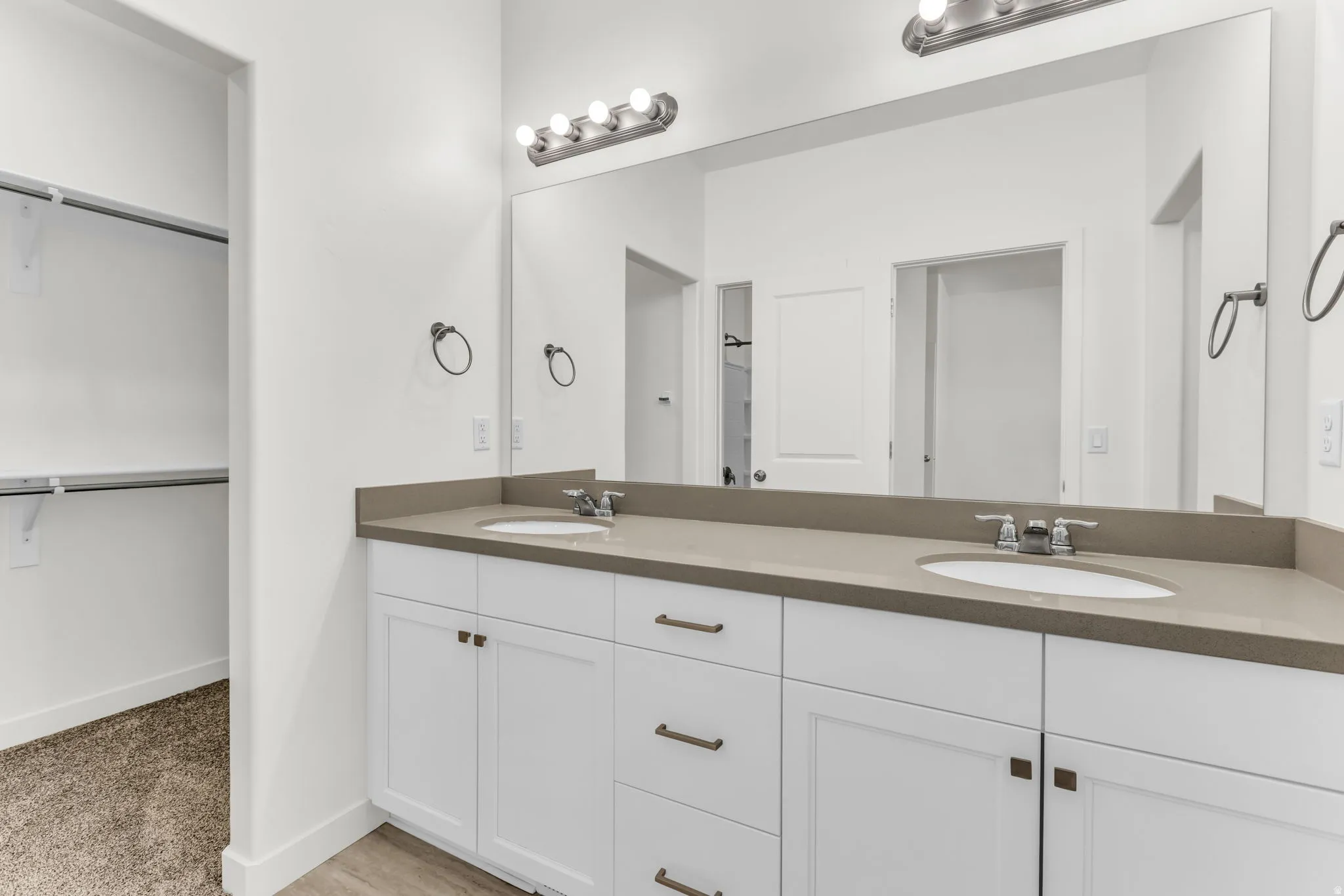 Spa-inspired dual-sink vanity featuring white cabinetry with brushed metal hardware, a spacious stone-finish countertop, and chrome vessel sinks