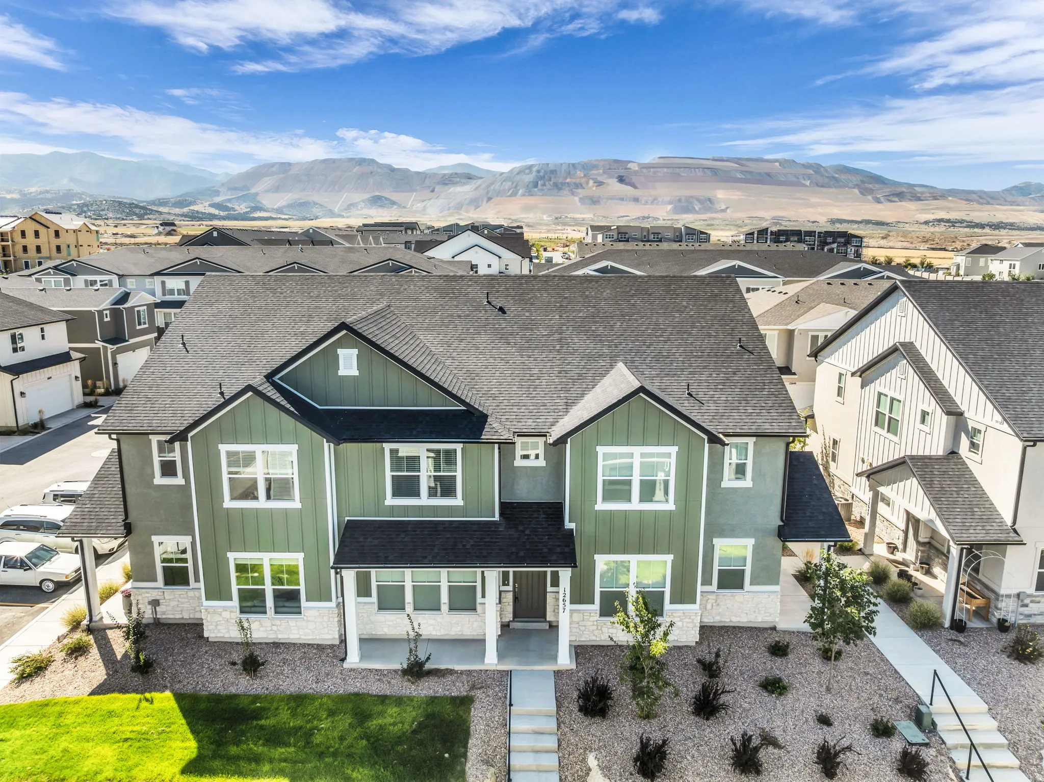 Modern two-story exterior with a covered porch, stone accents, and a dark shingle roof