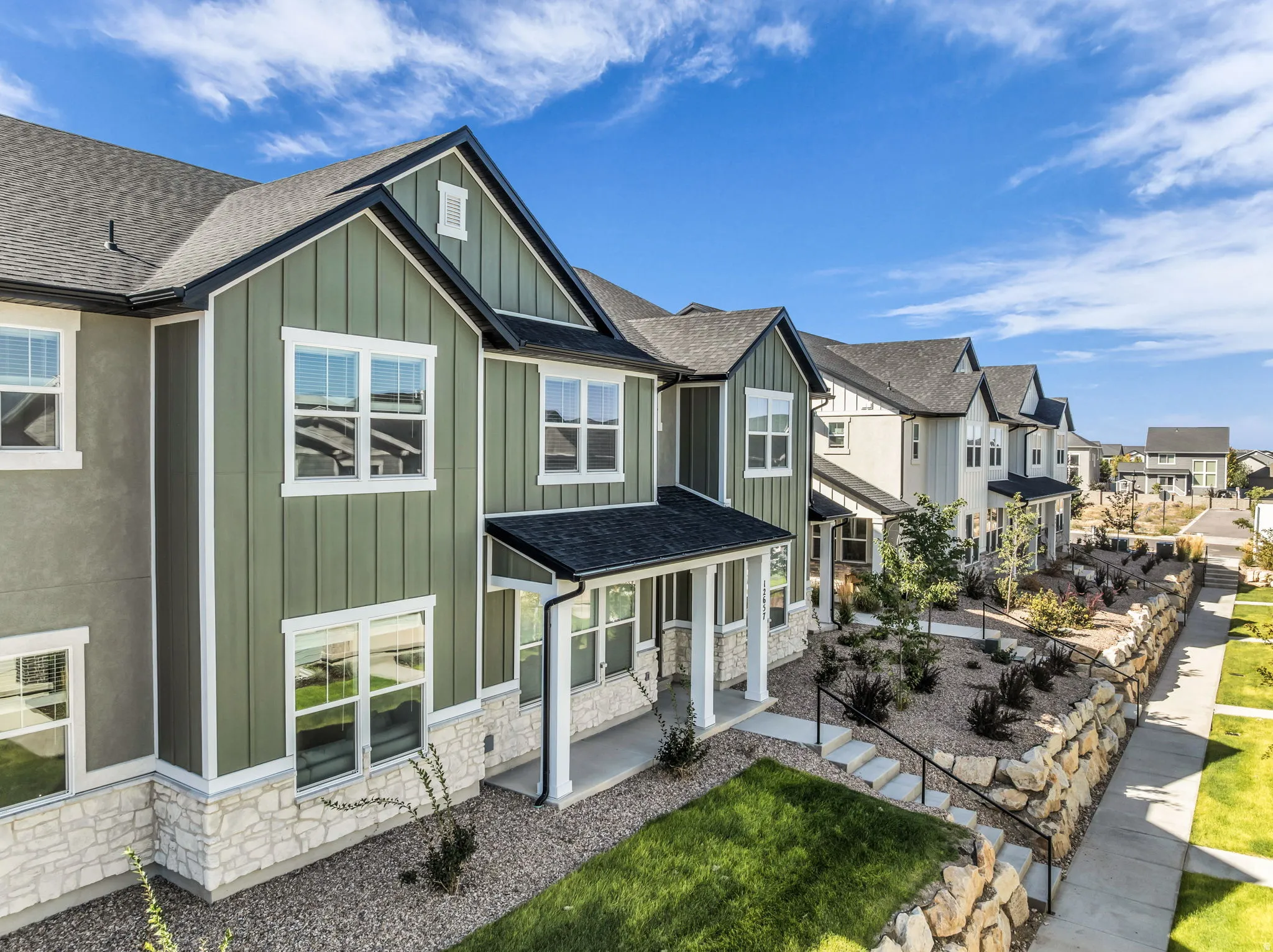 Exterior featuring board-and-batten siding, stone veneer accents, covered porch entry, and a pitched roof