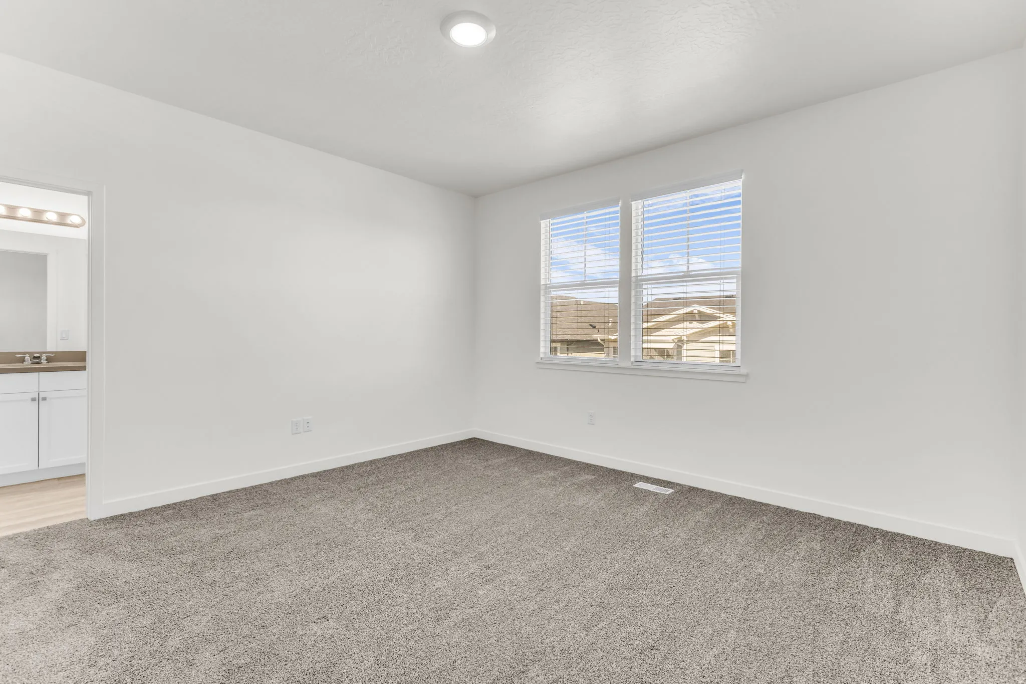 Neutral wall paint, plush carpet flooring, recessed ceiling lighting, and window blinds