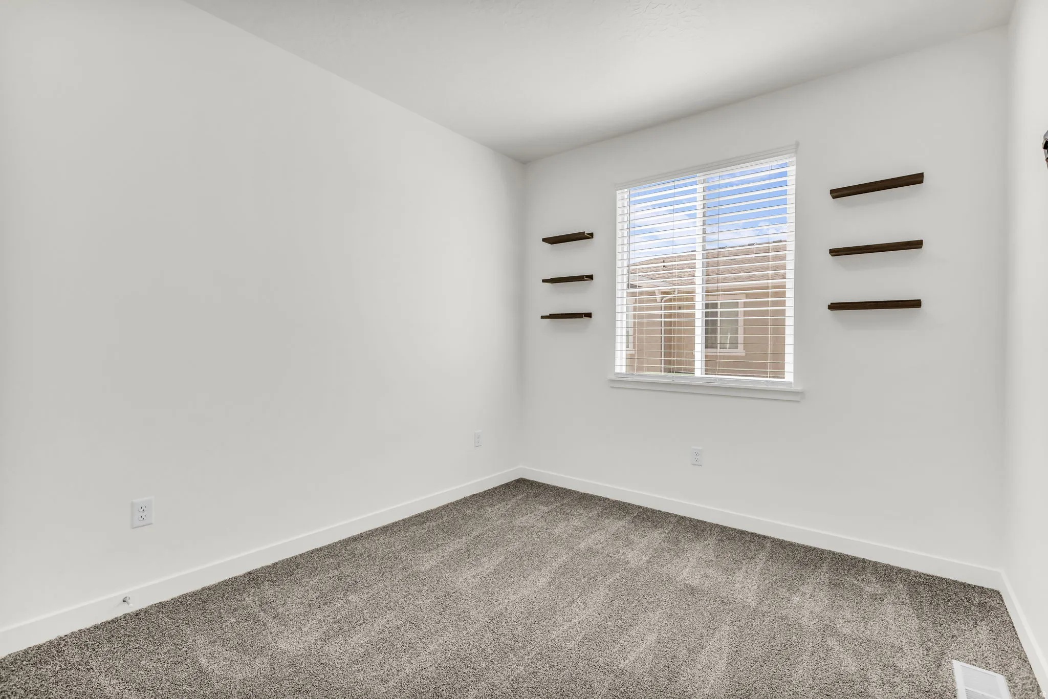 Carpeted flooring, white walls, and a window with horizontal blinds