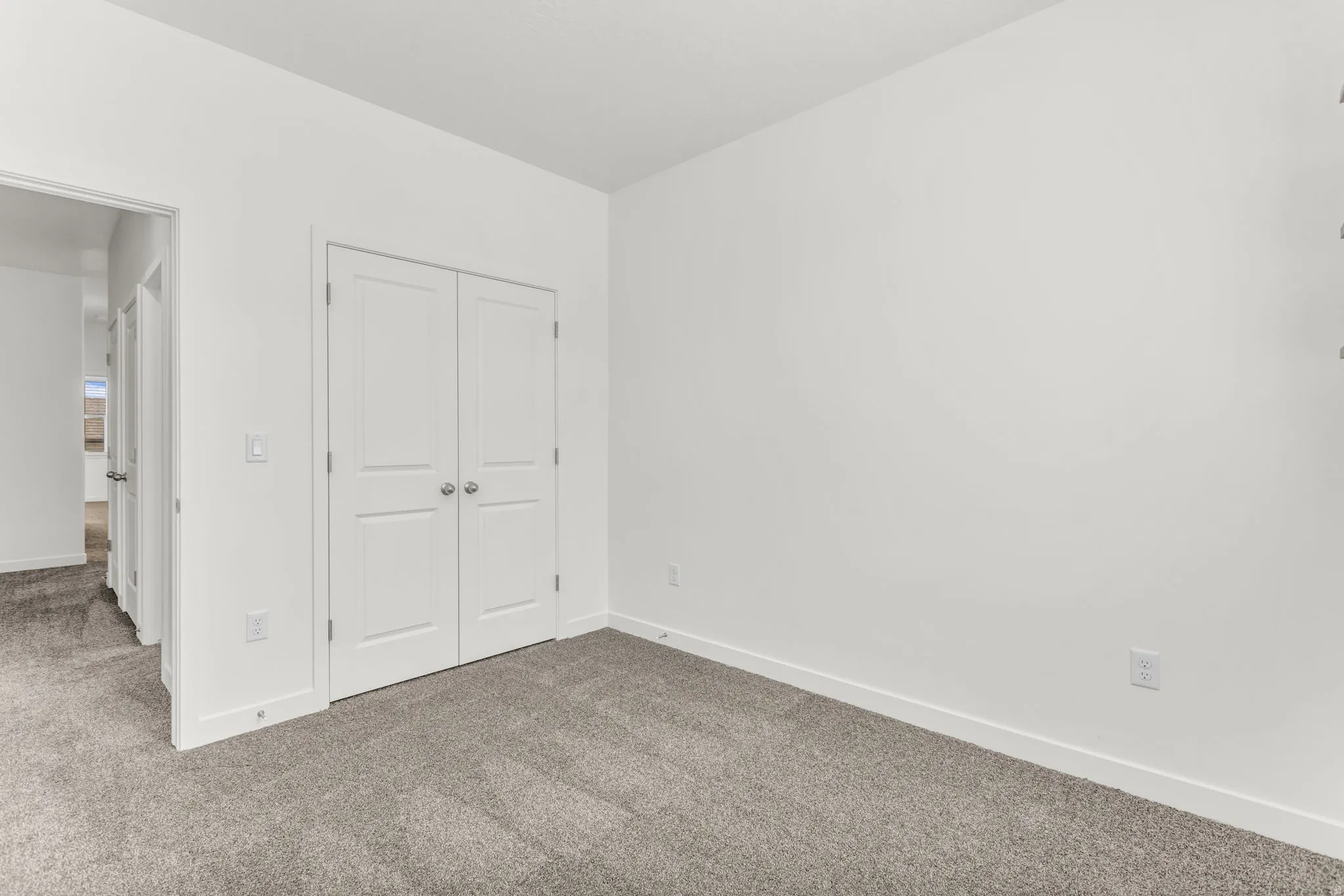 Neutral wall paint, gray carpeting, white trim, and white bi-fold doors
