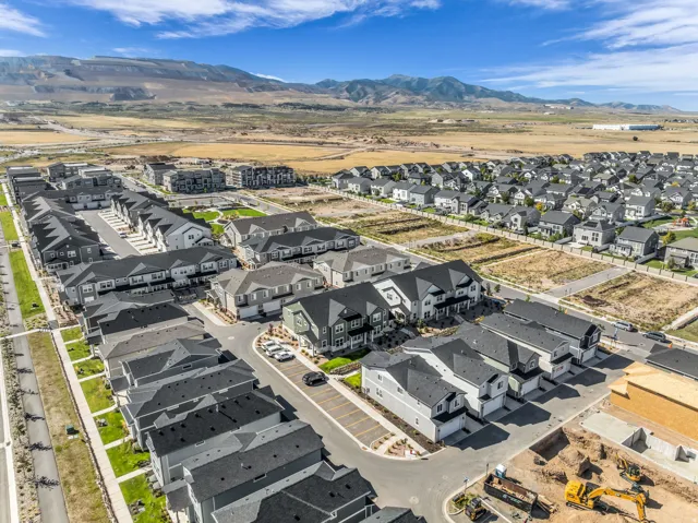 Expansive residential development with a mountain backdrop, featuring single-family homes and townhomes, paved streets, and undeveloped lots
