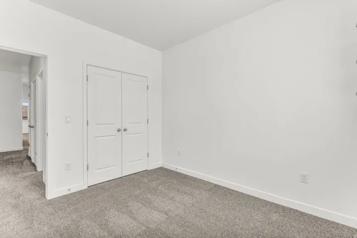 Neutral wall paint, gray carpeting, white trim, and white bi-fold doors