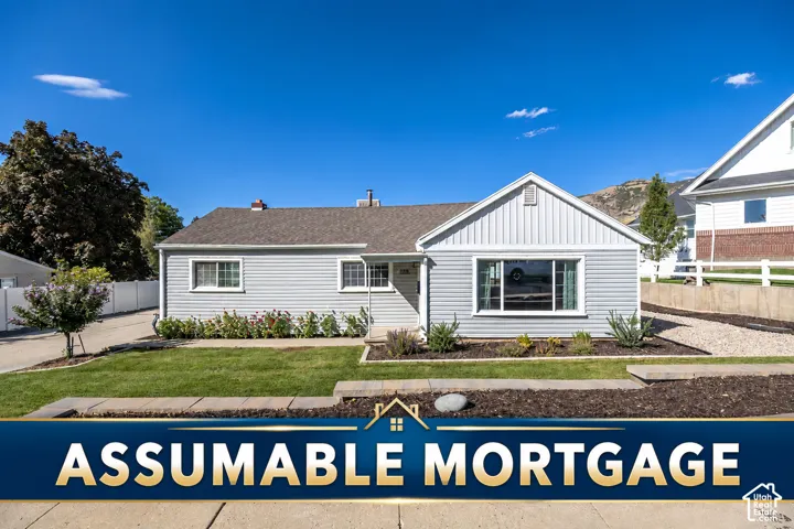Single-story residence featuring light-colored horizontal siding, vertical gable siding, a composition shingle roof, multi-pane windows, and terraced landscaping with stone retaining walls