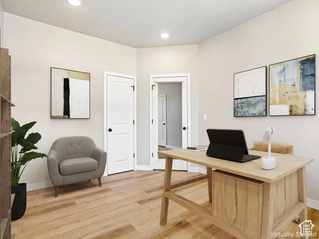 Recessed lighting, wood-finish flooring, white trim, and a built-in wooden desk