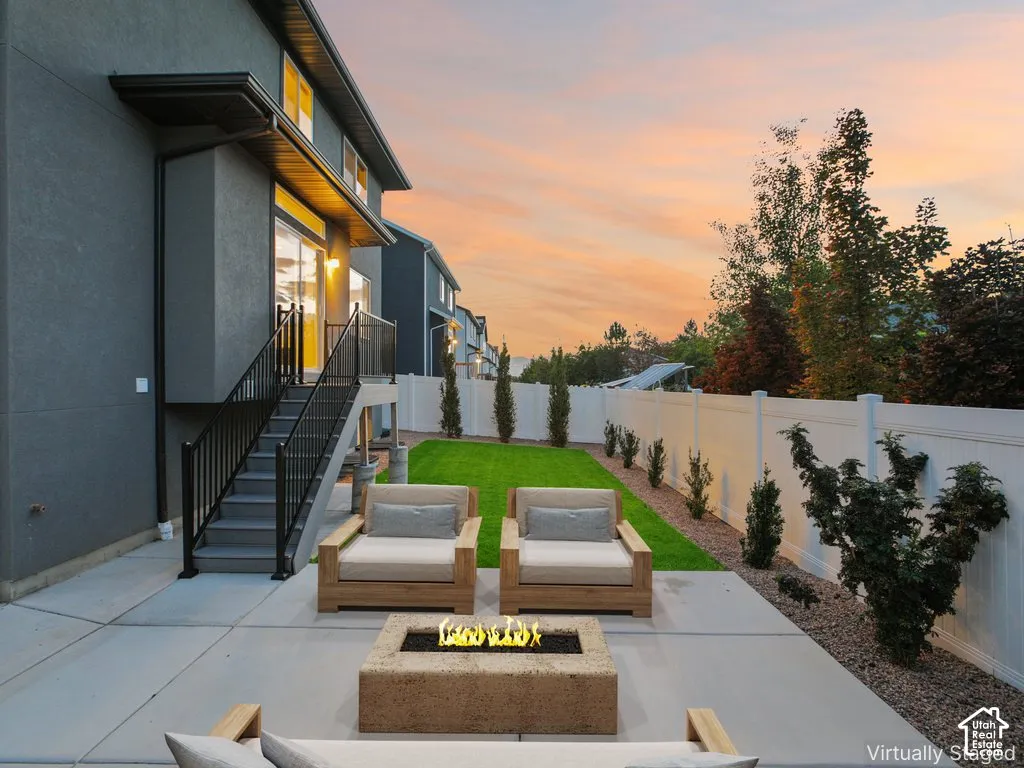 Concrete patio with a built-in fire pit, leading to a landscaped lawn