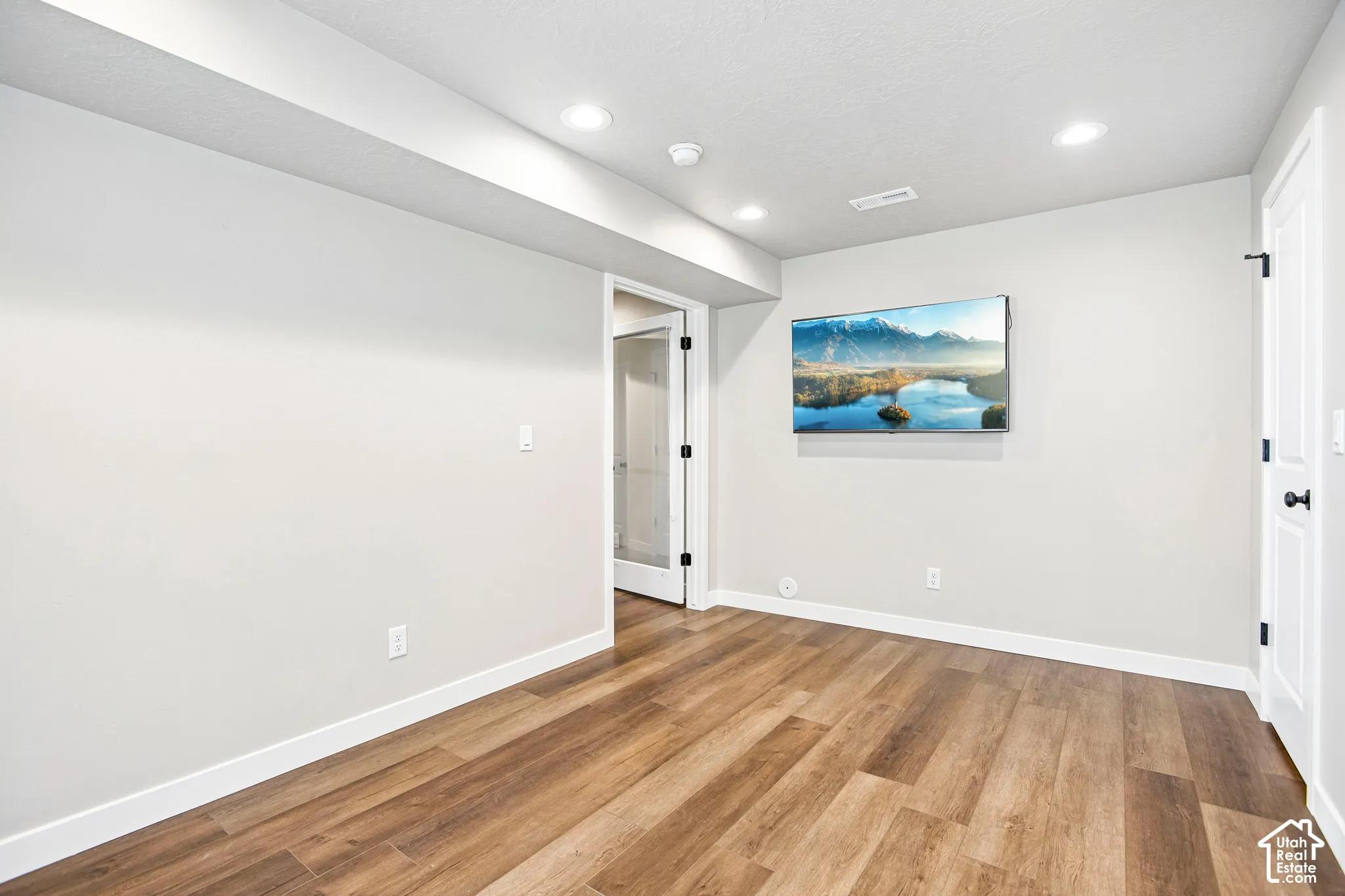 Wood-finish flooring, recessed lighting, white walls, and white trim