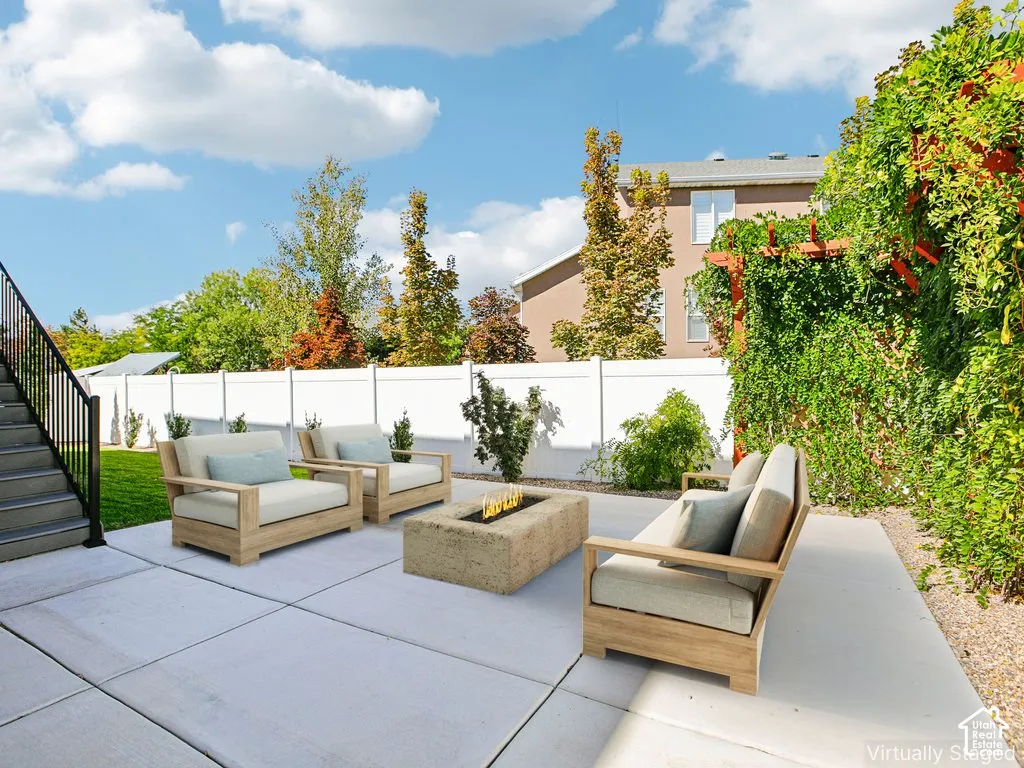Expansive concrete patio with a built-in fire pit, privacy fencing, and a trellised wall