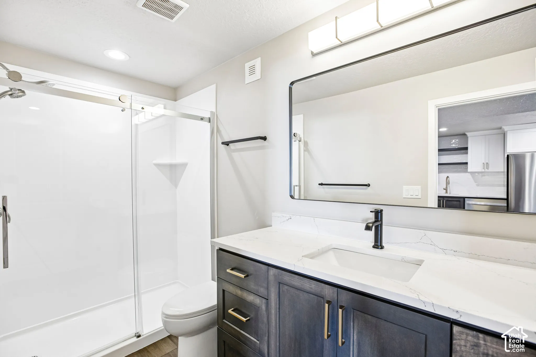 Dark wood-finish vanity with gold-tone hardware, white countertop with integrated sink, and matte black faucet