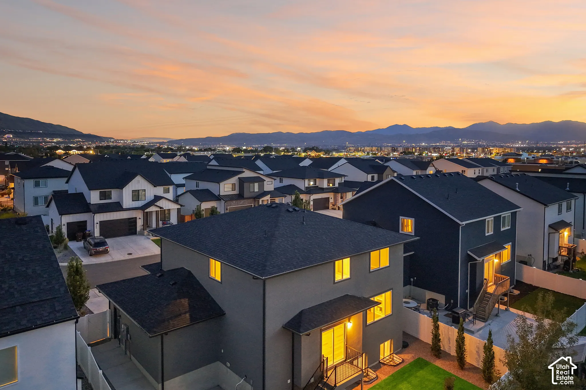 Modern residential community with distinct architectural styles, featuring dark roofing and mountain backdrops