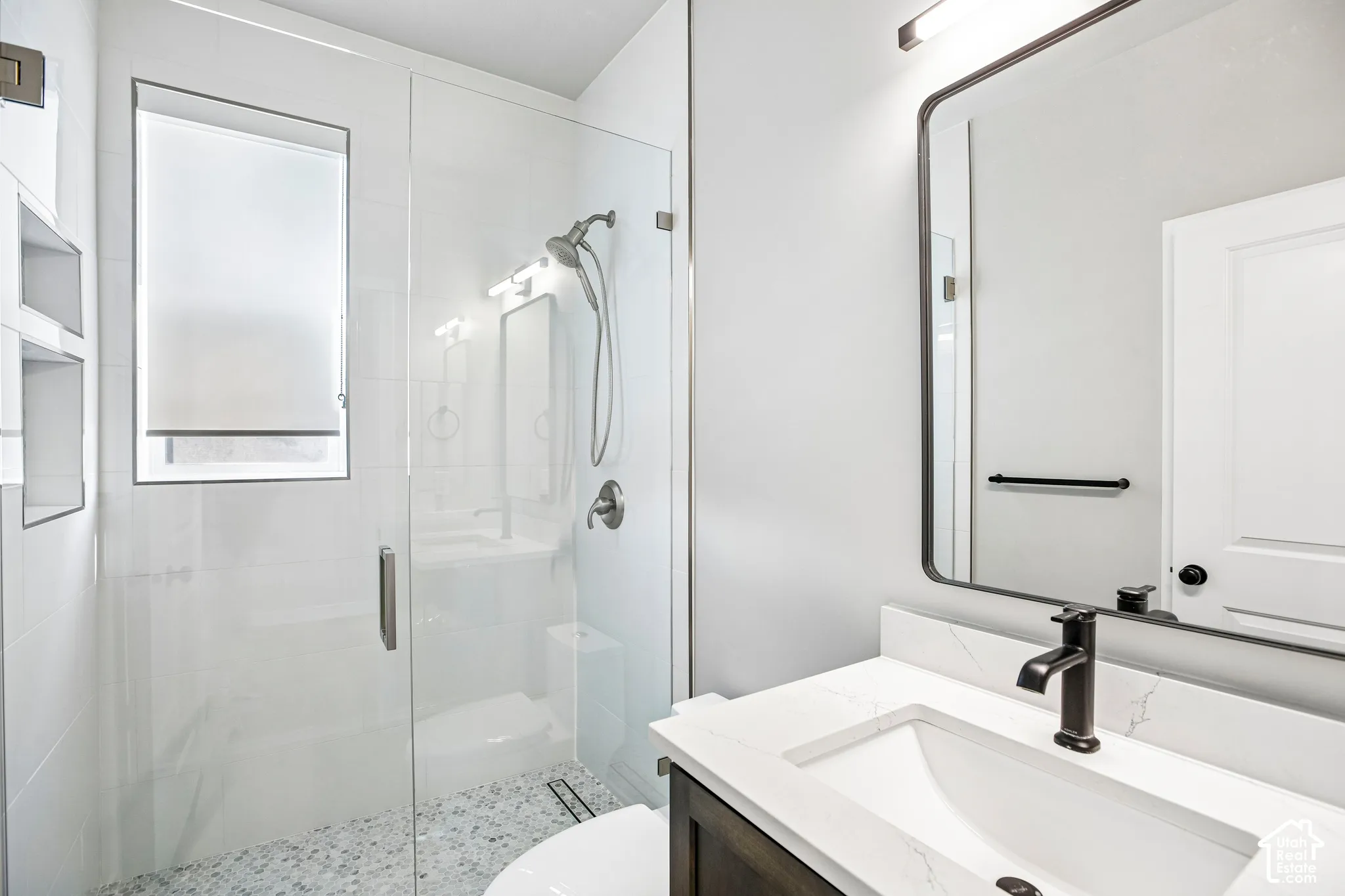 Glass-enclosed shower with pebble-tile flooring and an integrated niche