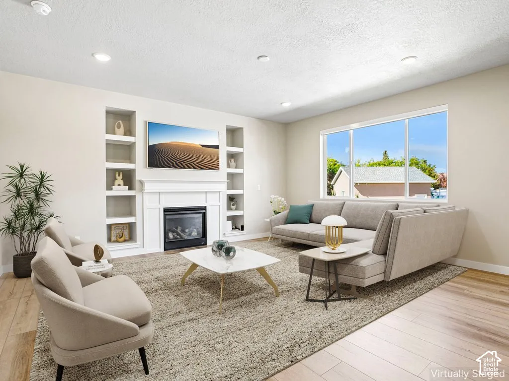 Recessed lighting, wood-finish flooring, built-in shelving, white fireplace surround, and a large multi-pane window