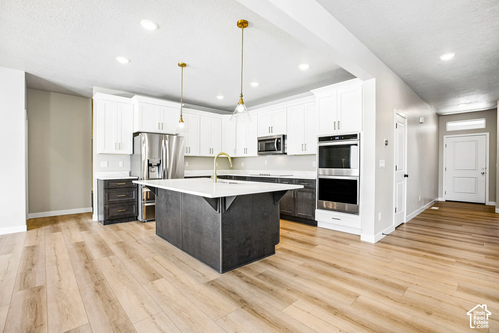 Kitchen featuring a central island with a solid surface countertop, stainless steel appliances, recessed lighting, and wood-finish flooring