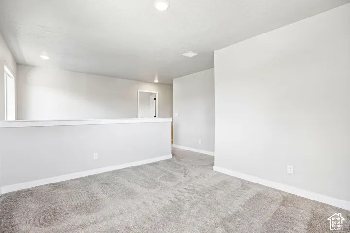 Open loft area featuring recessed lighting, a neutral color palette, and gray carpet