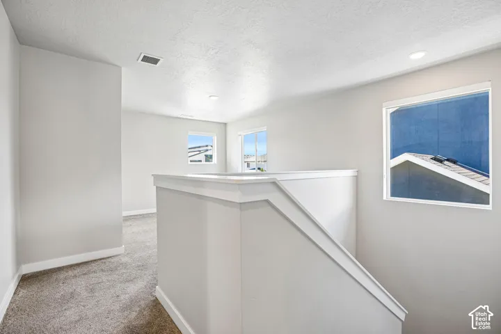 Upper-level landing featuring neutral carpeting, white wall paint, and recessed lighting