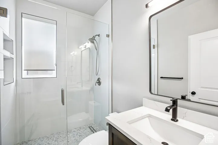 Glass-enclosed shower with pebble-tile flooring and an integrated niche