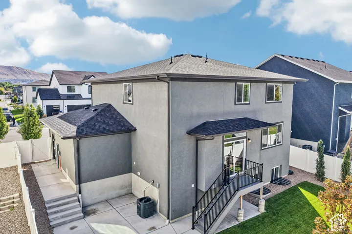 Stucco exterior with a multi-level concrete patio, private deck with metal railings, and a fenced yard with established lawn