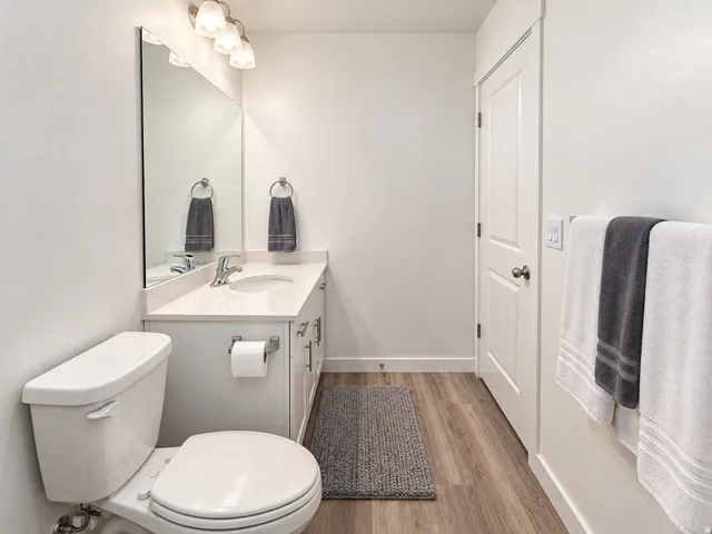 White vanity with an integrated sink, polished chrome faucet, rectangular mirror, and four-light sconce