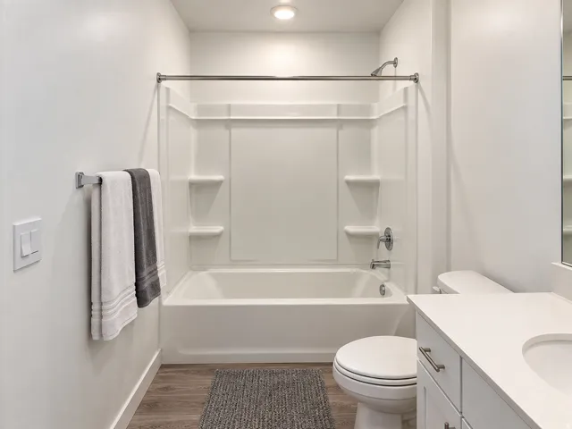 White tub/shower combination, chrome fixtures, wood-finish flooring, and a white vanity with integrated sink