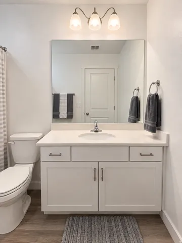 White vanity with a single basin sink, light-toned countertop, and brushed nickel hardware