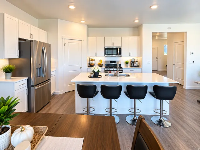 White cabinetry, stainless steel appliances, central island with seating, wood-finish flooring, and recessed lighting