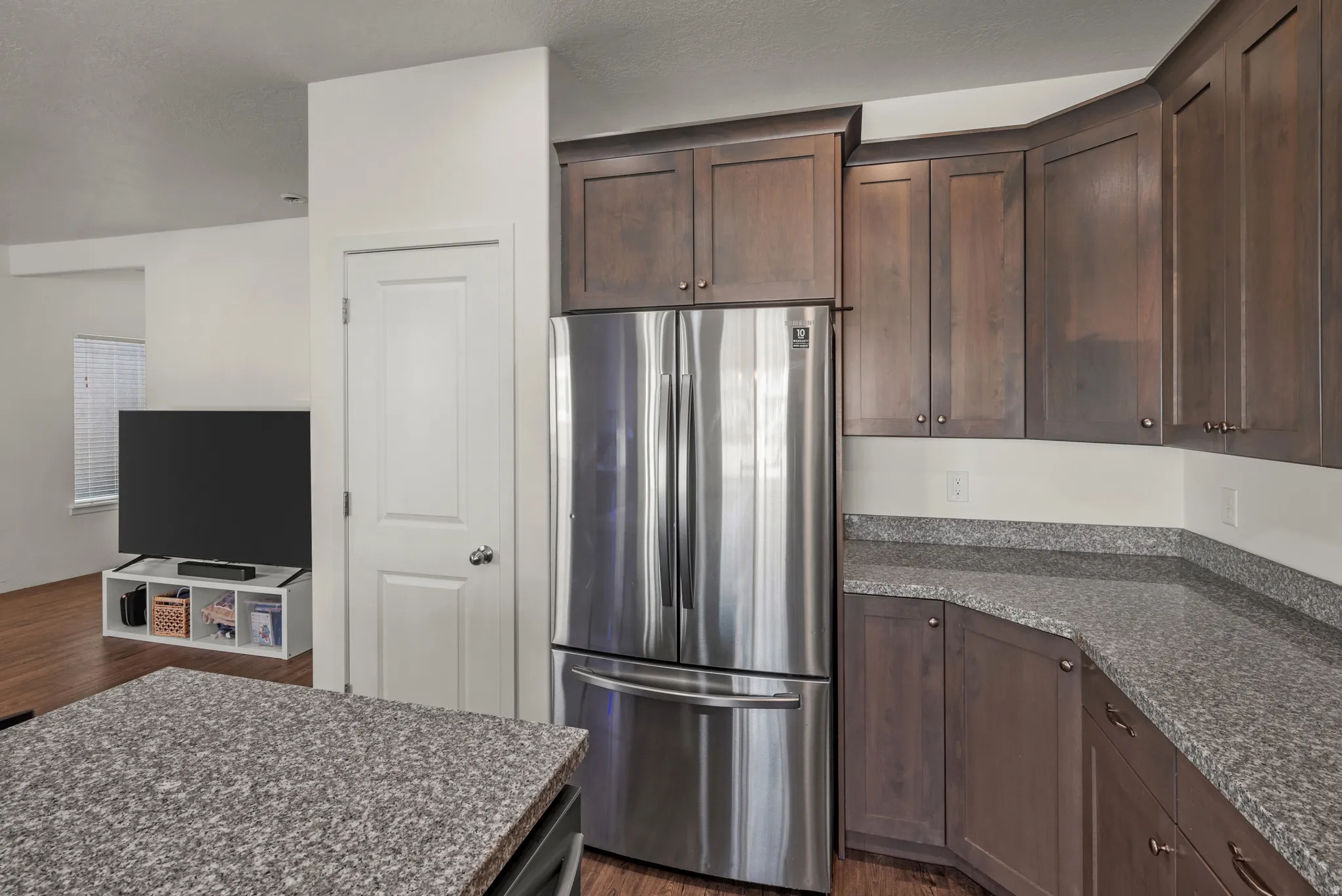 Stainless steel French door refrigerator, wood-finish cabinetry, and granite-look countertops