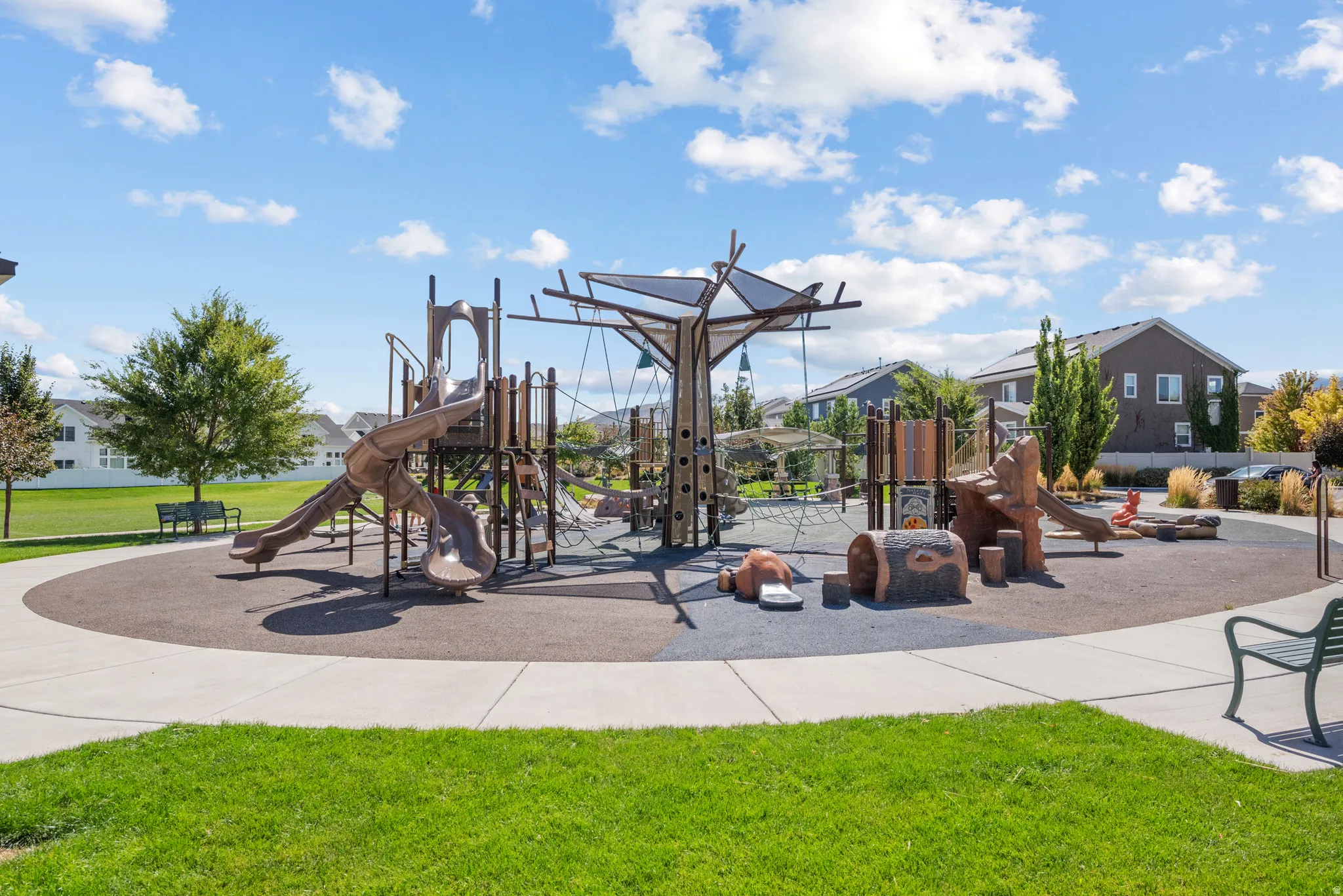 Community playground featuring multiple slides, climbing structures, and soft-surface ground cover