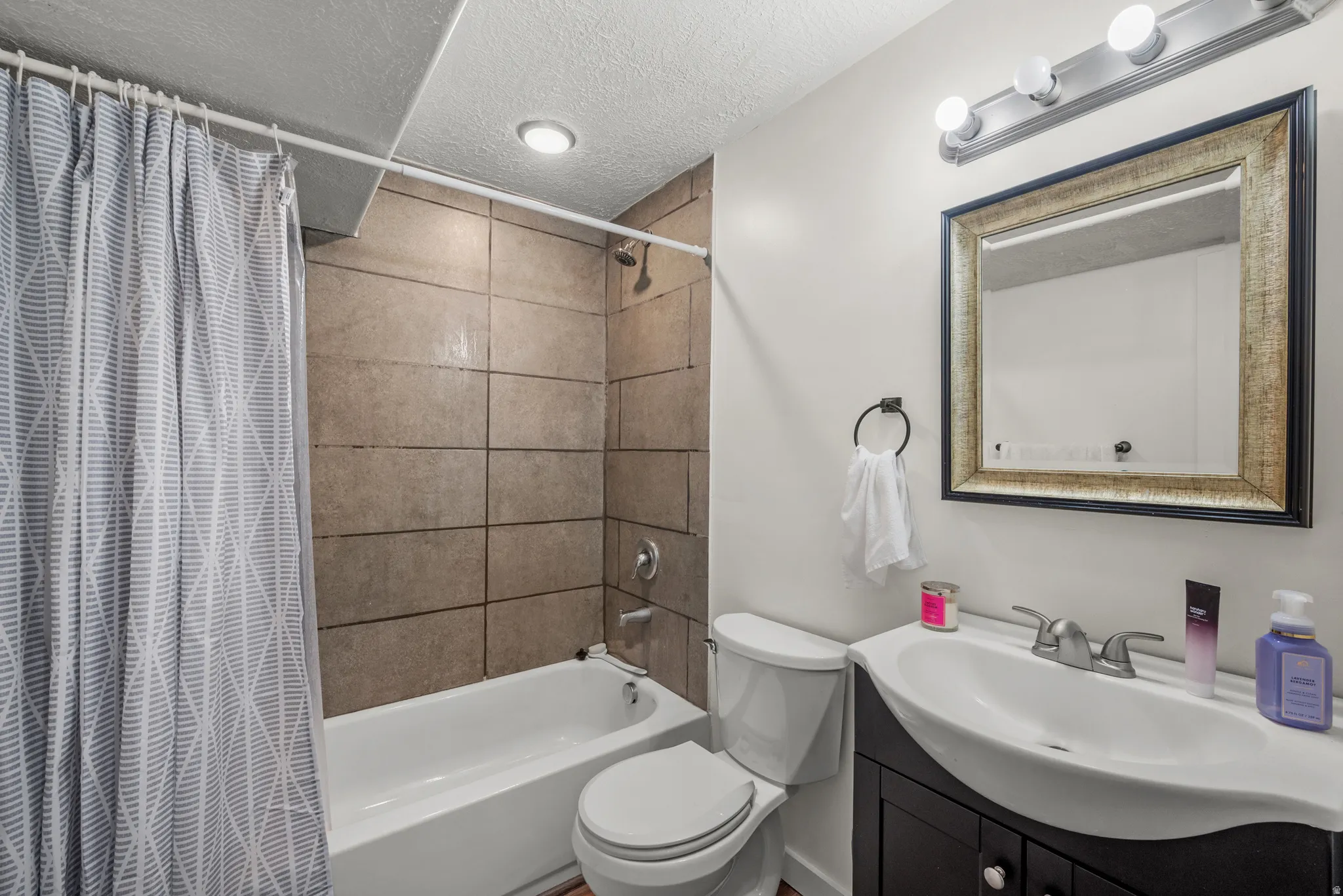 Bathroom with a framed mirror, vanity with an integrated sink, tiled shower surround, and recessed lighting
