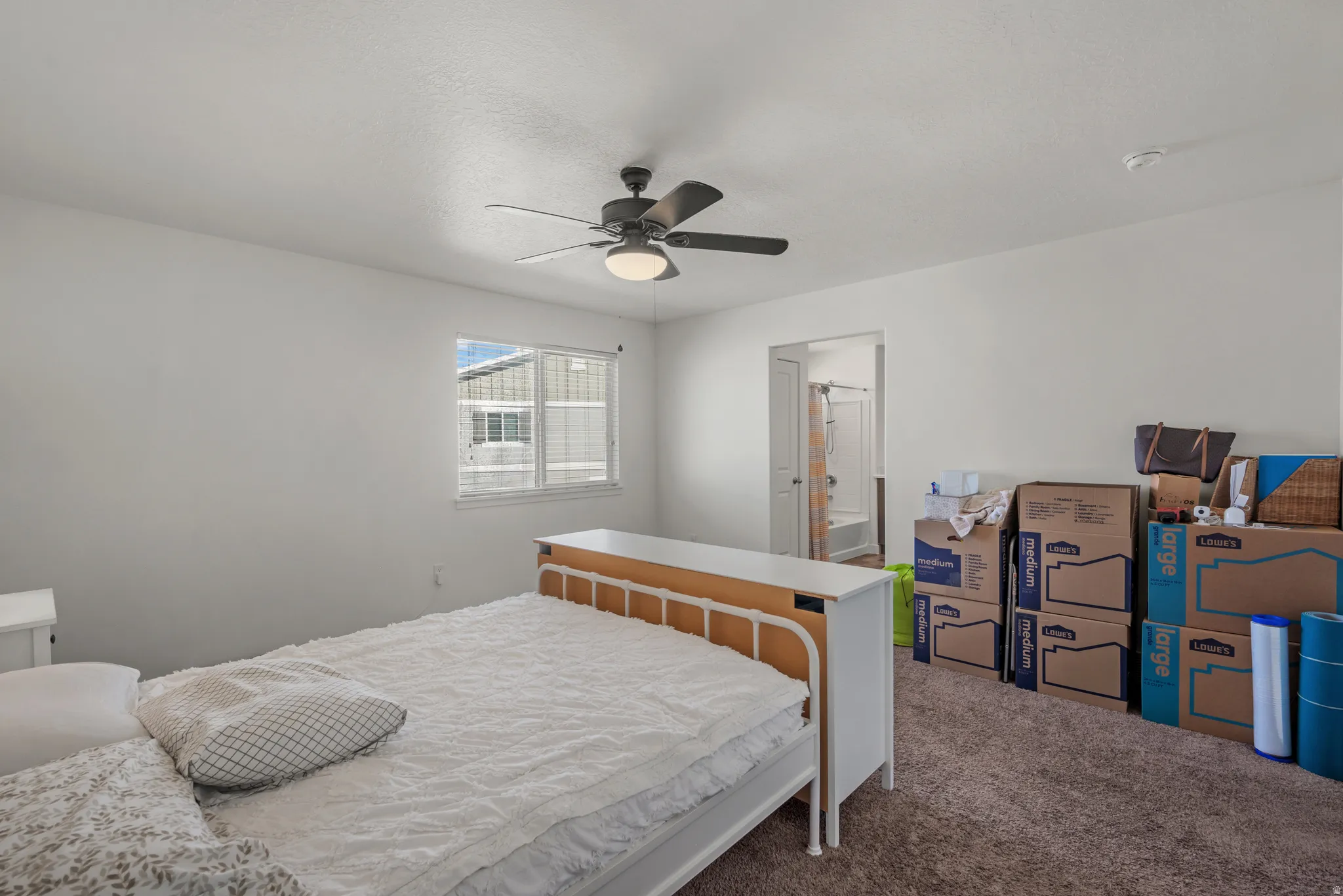 Carpeted flooring, white walls, ceiling fan with integrated lighting, and a window with white trim