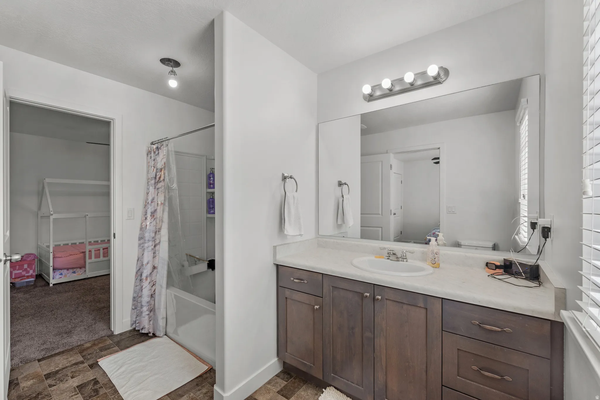 Bathroom featuring a vanity with dark wood-finish cabinetry, a single basin sink, and a large mirror with overhead lighting