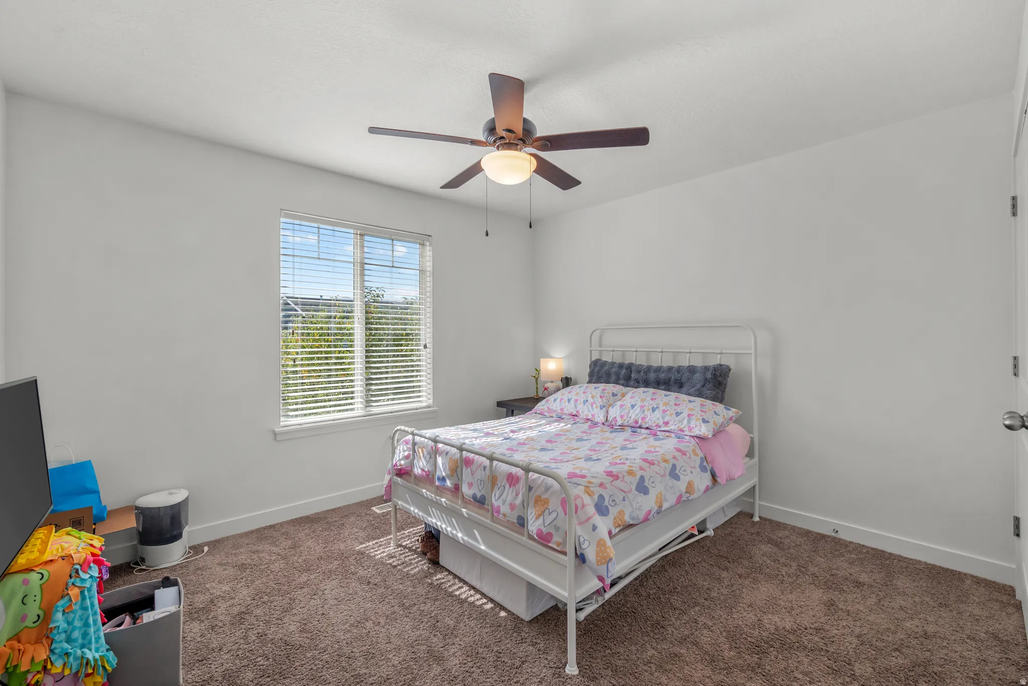 Carpeted room featuring a ceiling fan with integrated lighting, a window with blinds, and white walls