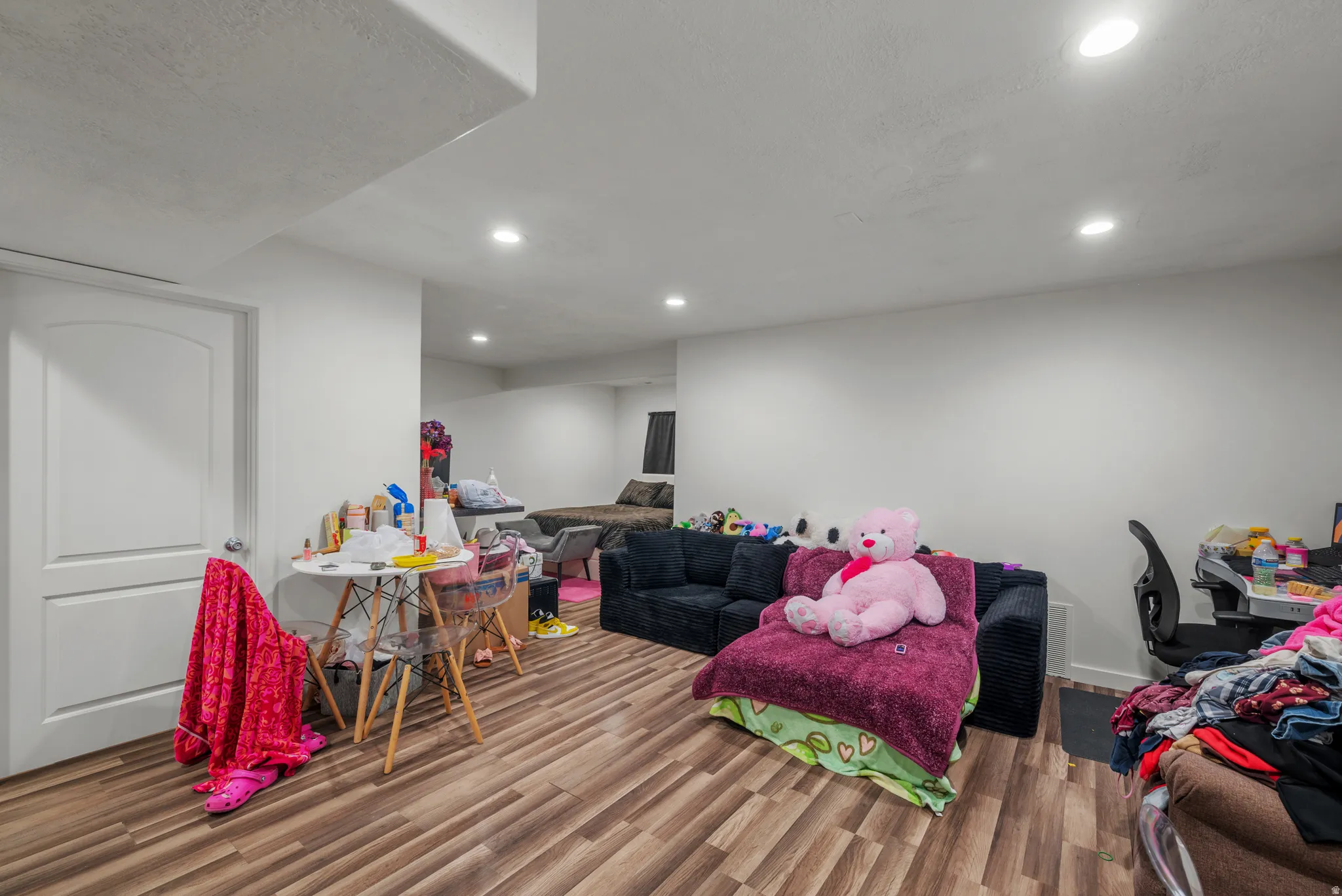 Wood-finish flooring throughout, complemented by recessed ceiling lighting and white painted walls